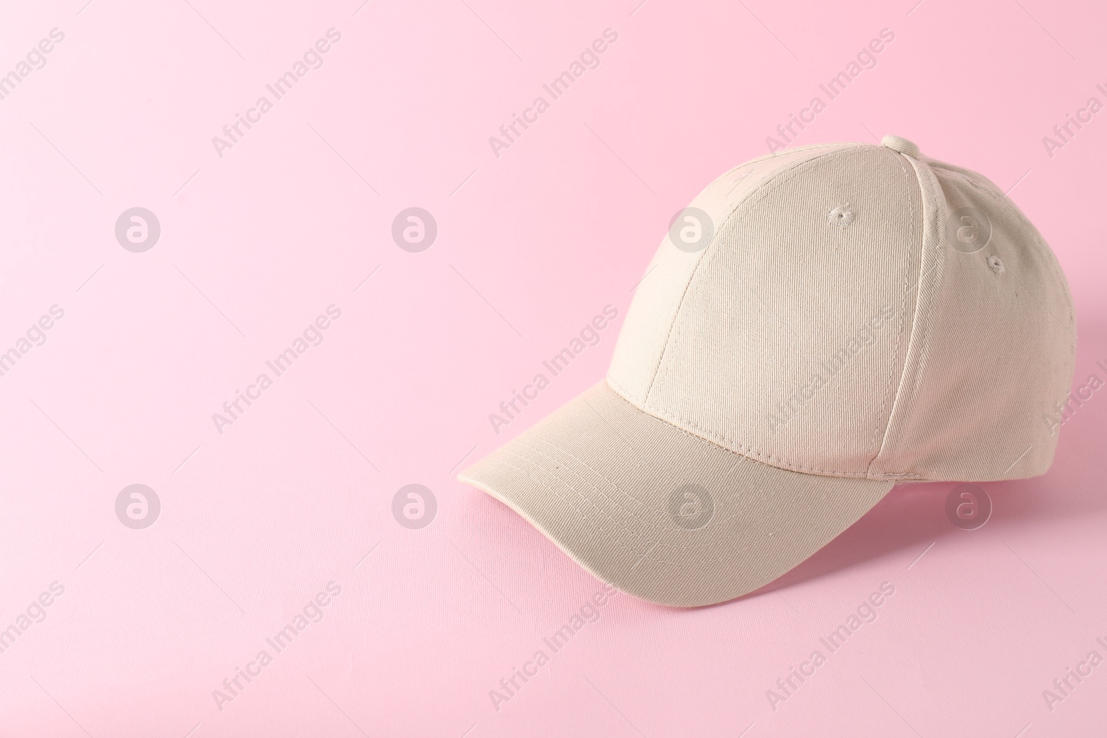 Photo of Stylish baseball cap on pink background. Mockup for design