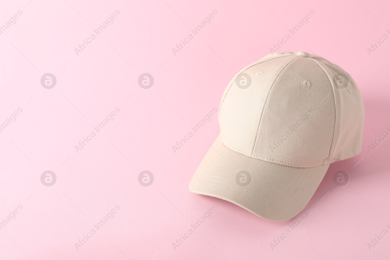 Photo of Stylish baseball cap on pink background. Mockup for design