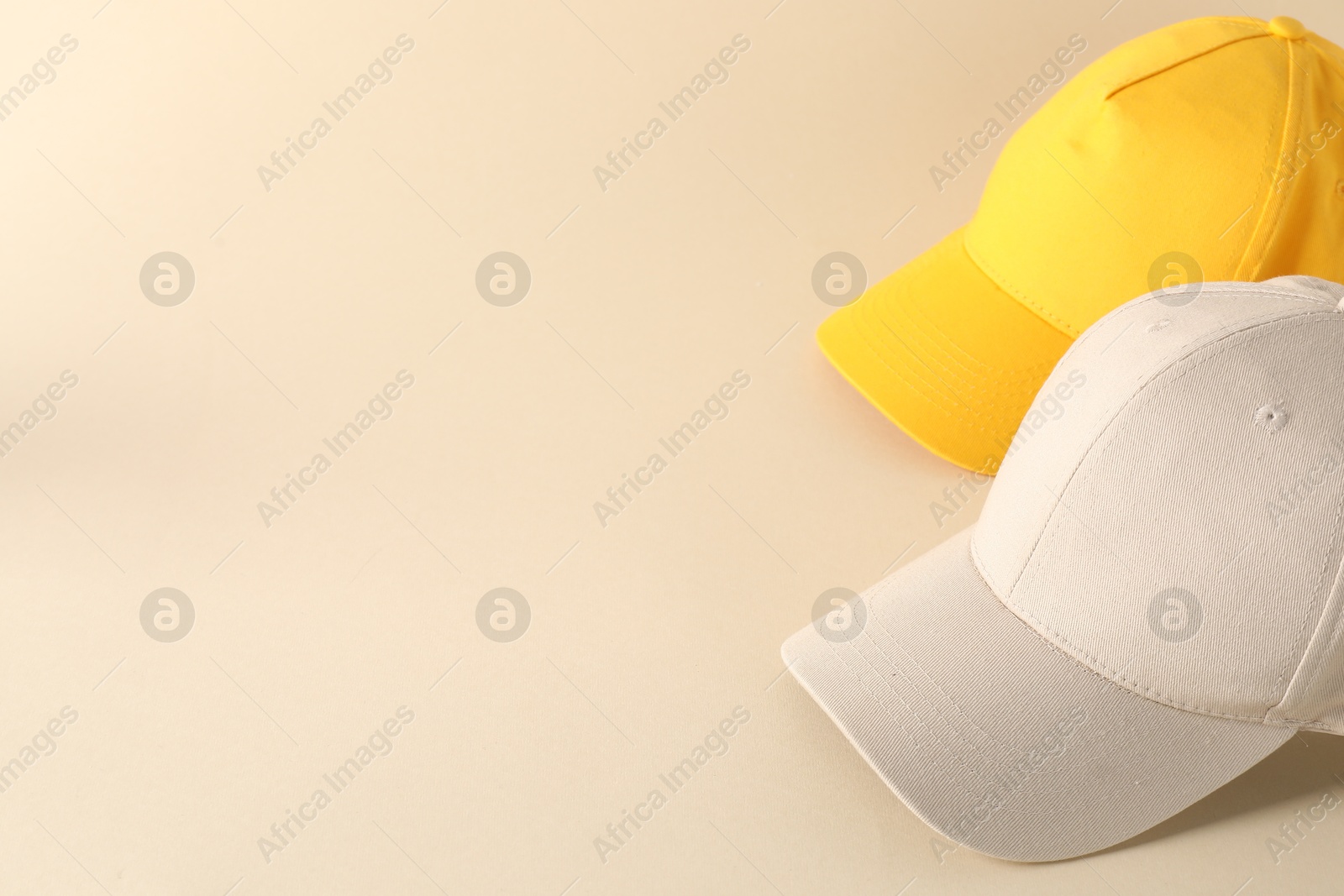 Photo of Stylish baseball caps on beige background. Mockup for design