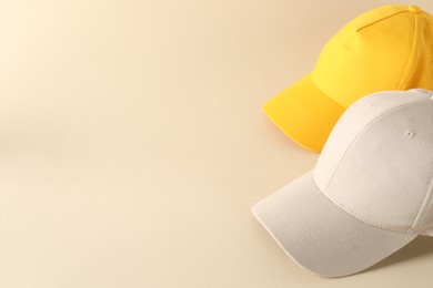 Photo of Stylish baseball caps on beige background. Mockup for design