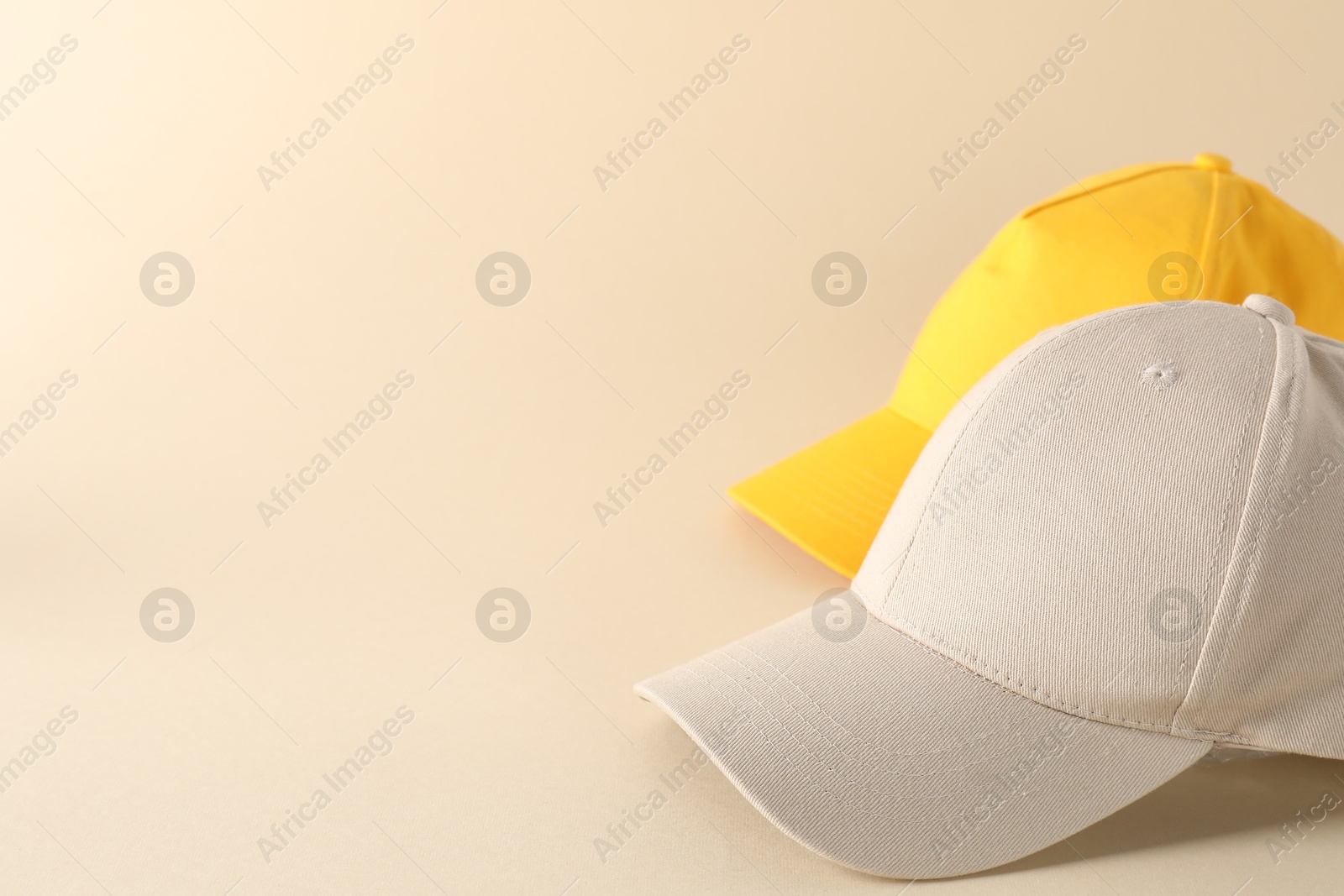 Photo of Stylish baseball caps on beige background. Mockup for design