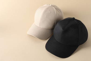 Photo of Stylish baseball caps on beige background. Mockup for design