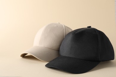 Photo of Stylish baseball caps on beige background. Mockup for design