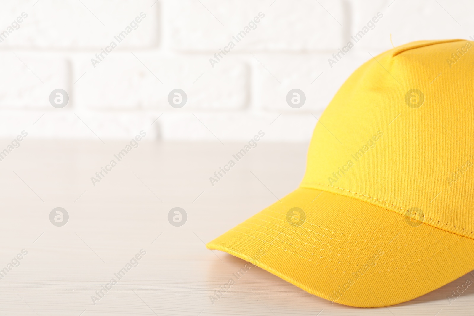 Photo of Stylish yellow baseball cap on wooden table, closeup. Mockup for design