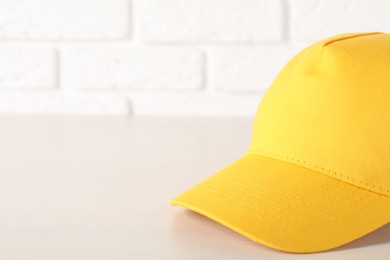 Photo of Stylish yellow baseball cap on wooden table, closeup. Mockup for design