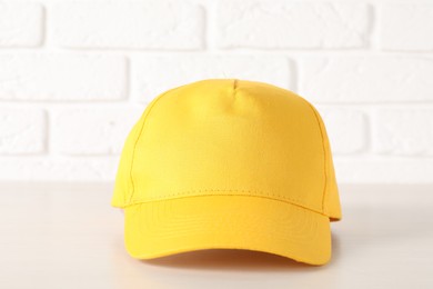 Photo of Stylish yellow baseball cap on wooden table, closeup. Mockup for design