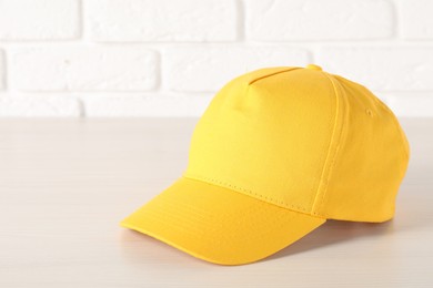 Photo of Stylish yellow baseball cap on wooden table, closeup. Mockup for design