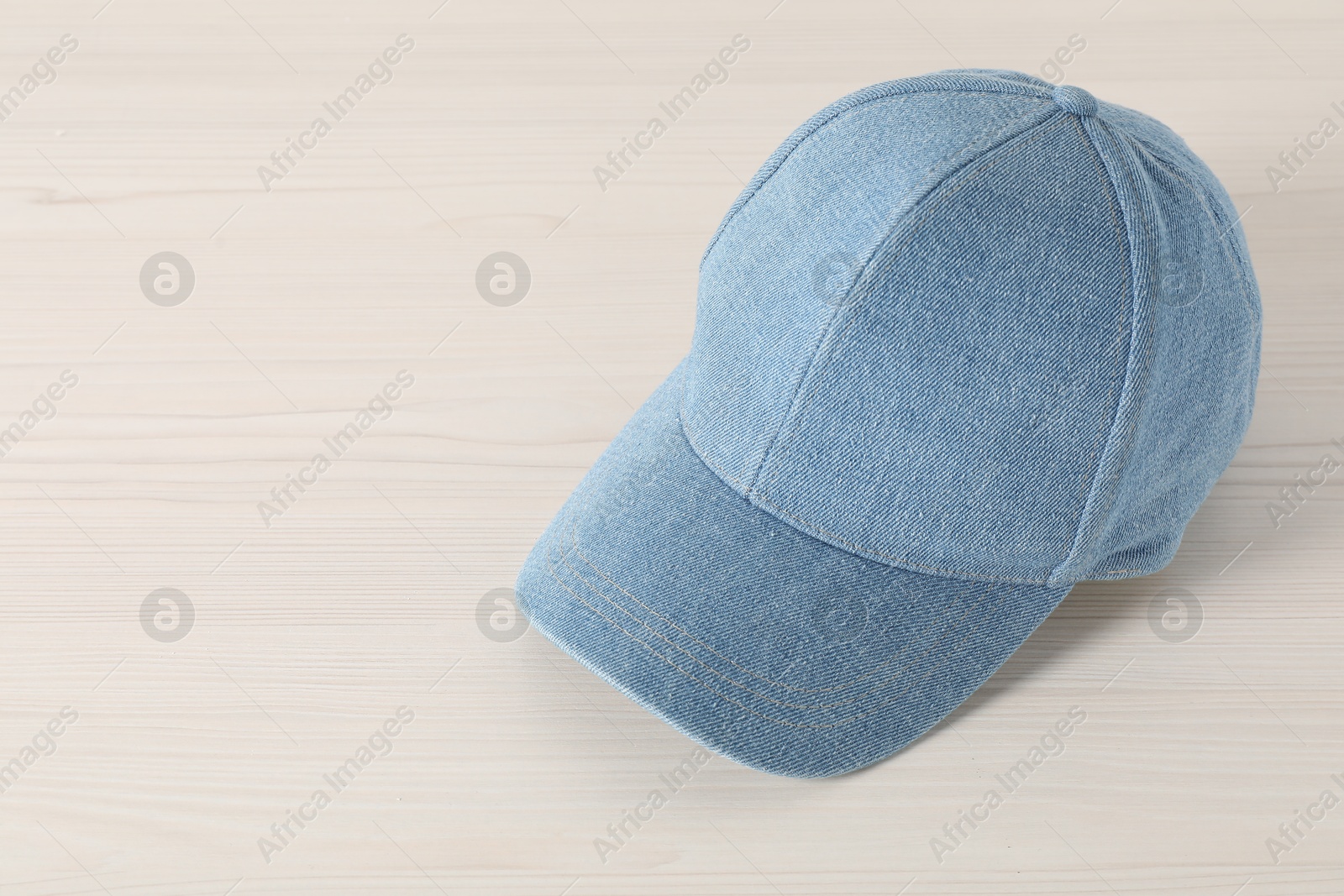 Photo of Stylish denim baseball cap on wooden table. Mockup for design