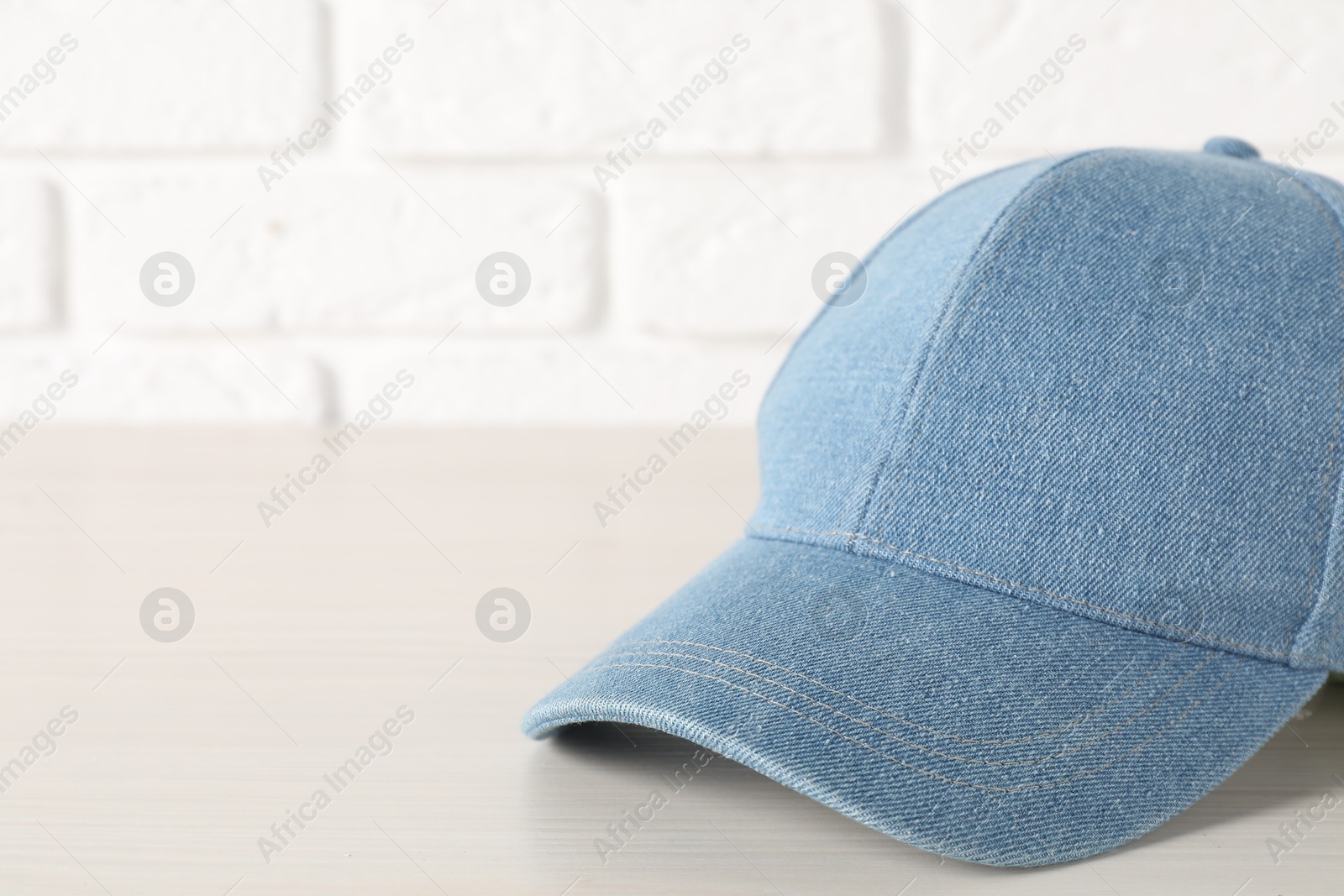 Photo of Stylish denim baseball cap on wooden table, closeup. Mockup for design