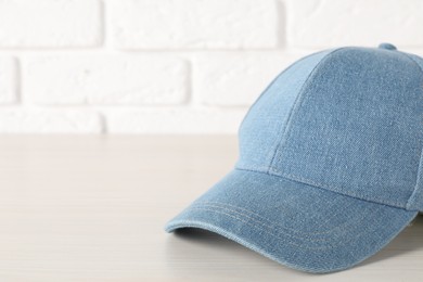 Photo of Stylish denim baseball cap on wooden table, closeup. Mockup for design