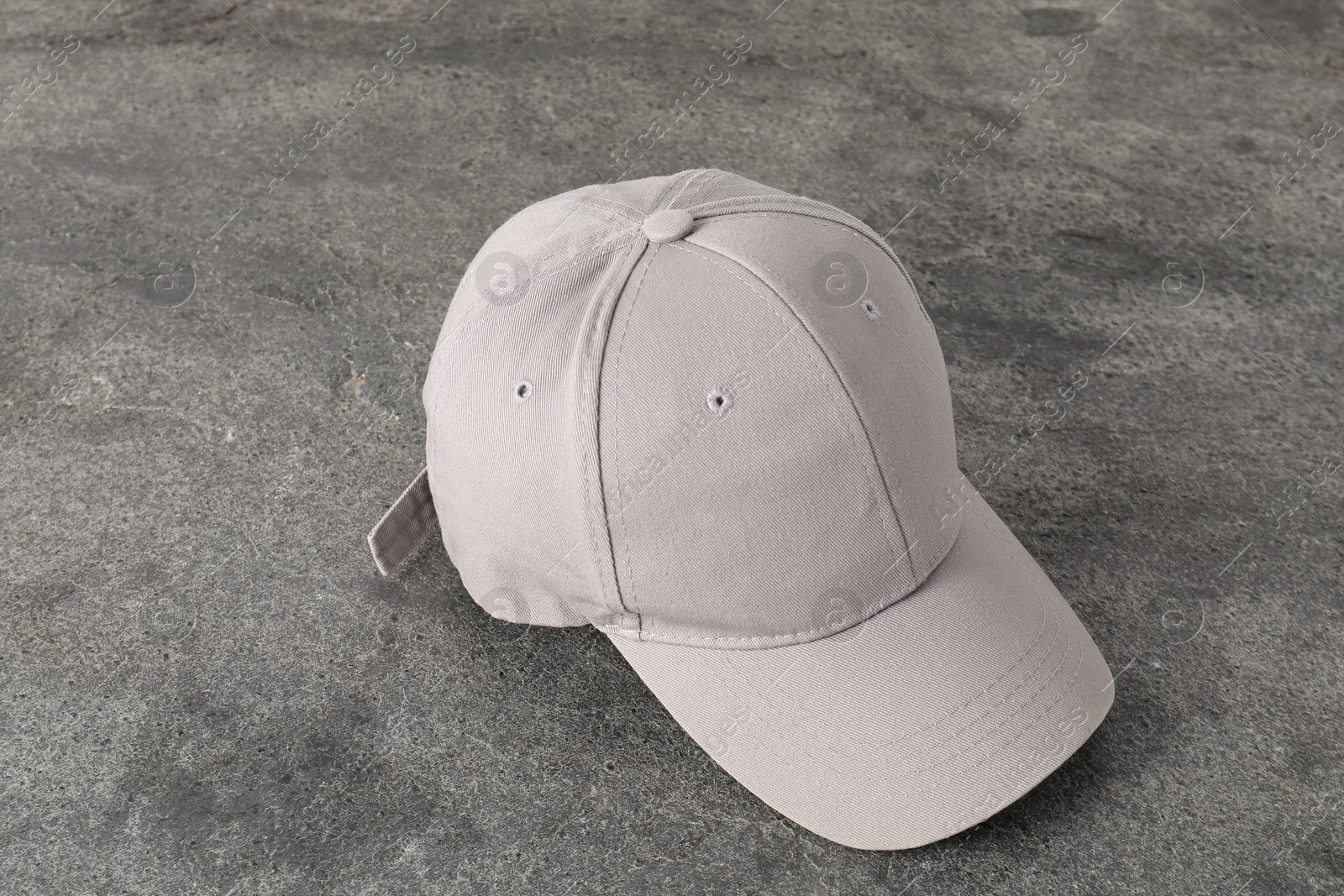 Photo of Stylish baseball cap on grey textured surface. Mockup for design