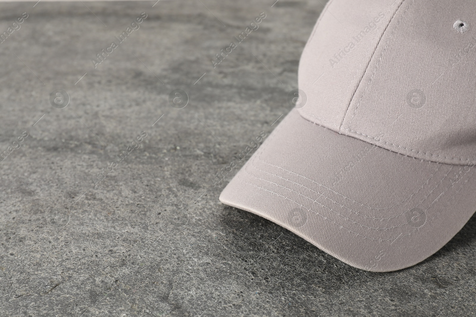 Photo of Stylish baseball cap on grey textured surface, closeup. Mockup for design