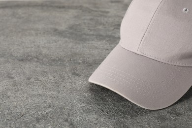 Photo of Stylish baseball cap on grey textured surface, closeup. Mockup for design