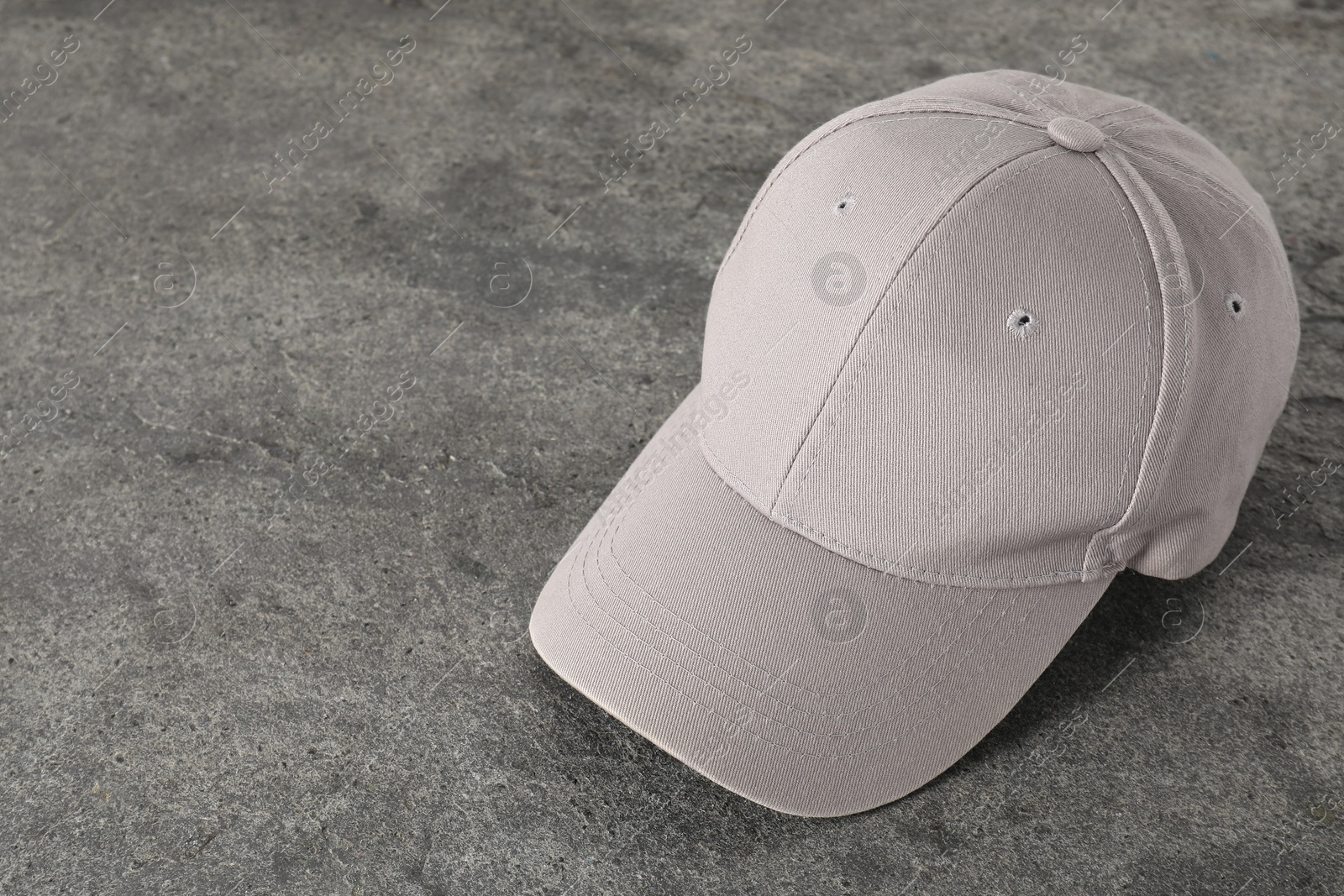 Photo of Stylish baseball cap on grey textured surface. Mockup for design