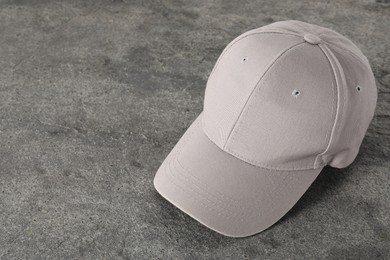 Photo of Stylish baseball cap on grey textured surface. Mockup for design