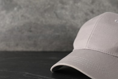 Photo of Stylish baseball cap on dark textured table, closeup. Mockup for design