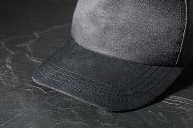 Photo of Stylish baseball cap on dark textured table, closeup. Mockup for design