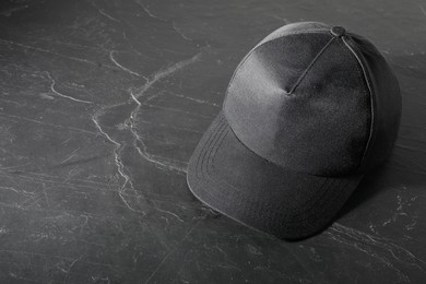 Photo of Stylish baseball cap on dark textured table. Mockup for design