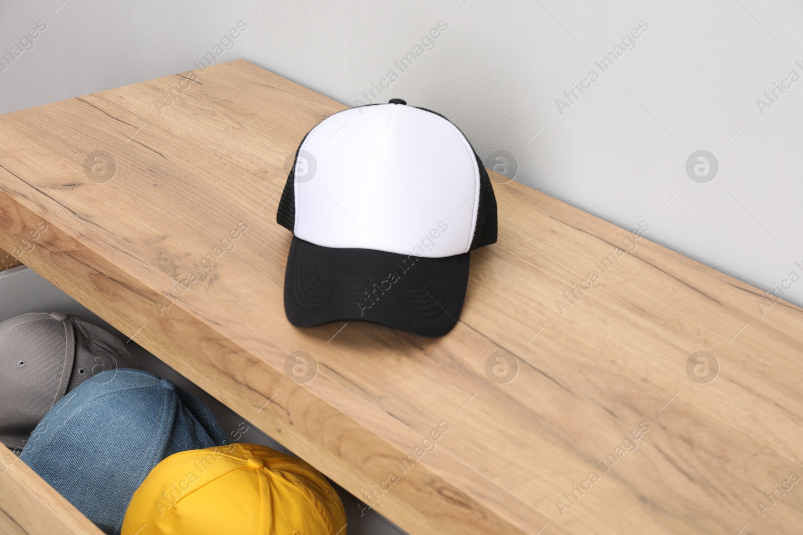 Photo of Wooden chest of drawers with stylish baseball caps. Mockup for design