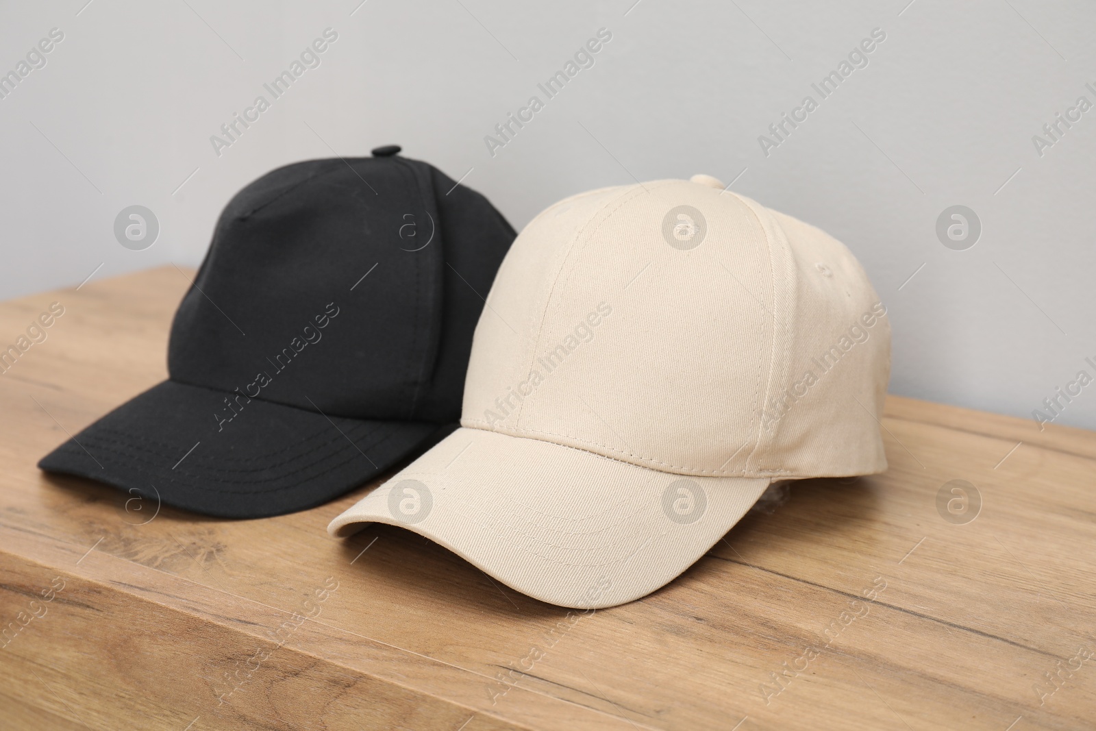 Photo of Stylish baseball caps on wooden table. Mockup for design