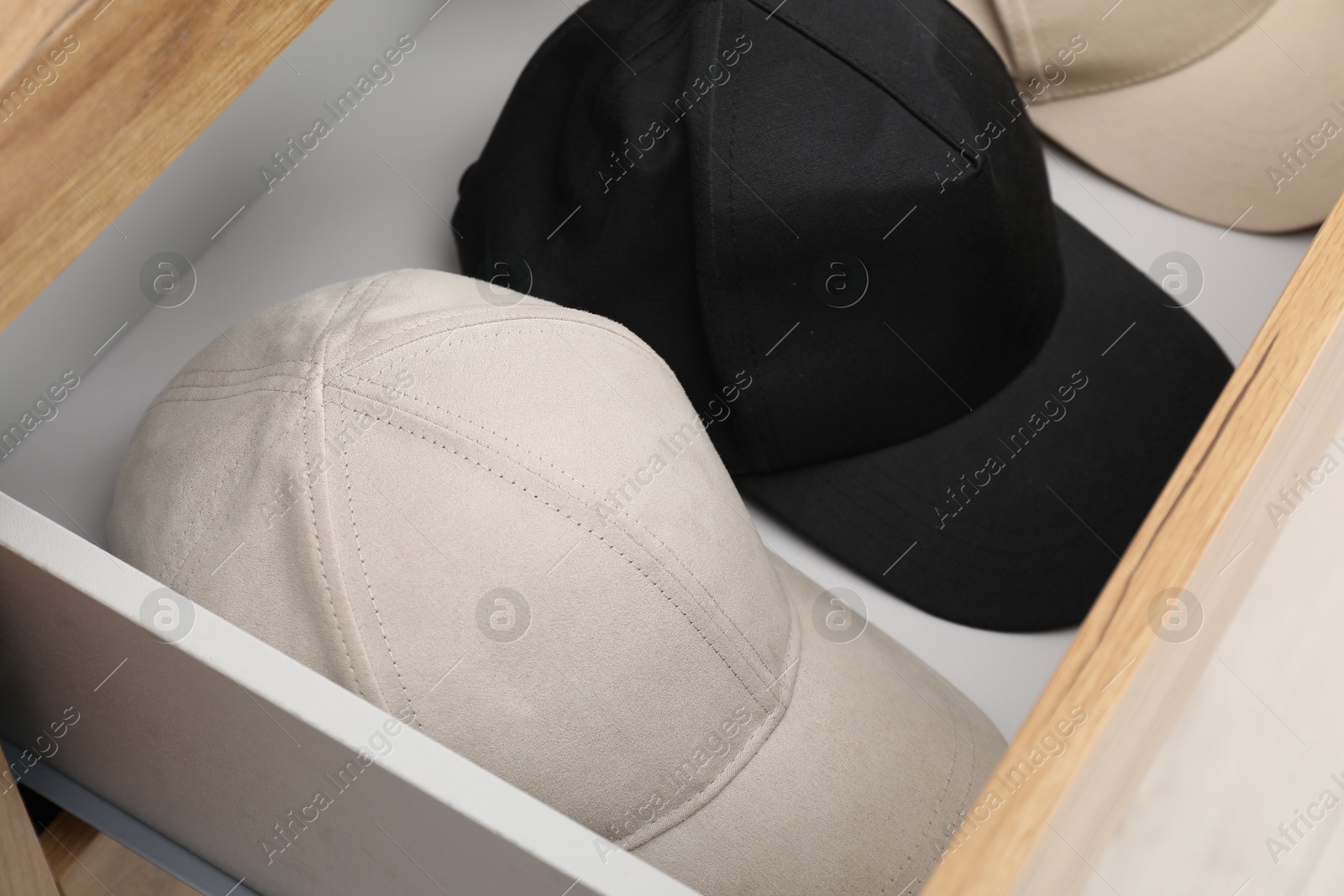 Photo of Stylish baseball caps in chest of drawers. Mockup for design