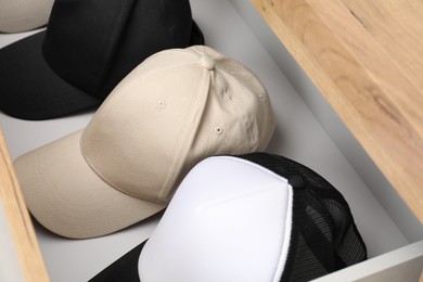 Photo of Stylish baseball caps in chest of drawers. Mockup for design