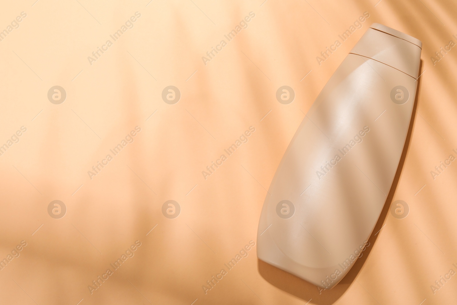 Photo of Shampoo in bottle on pale orange background, top view. Space for text