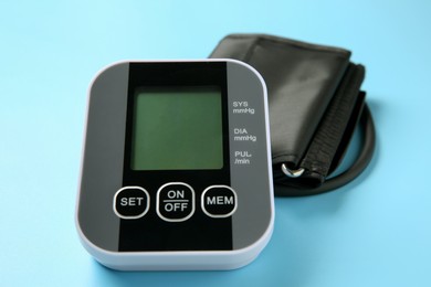 Photo of Blood pressure measuring device on light blue background, closeup