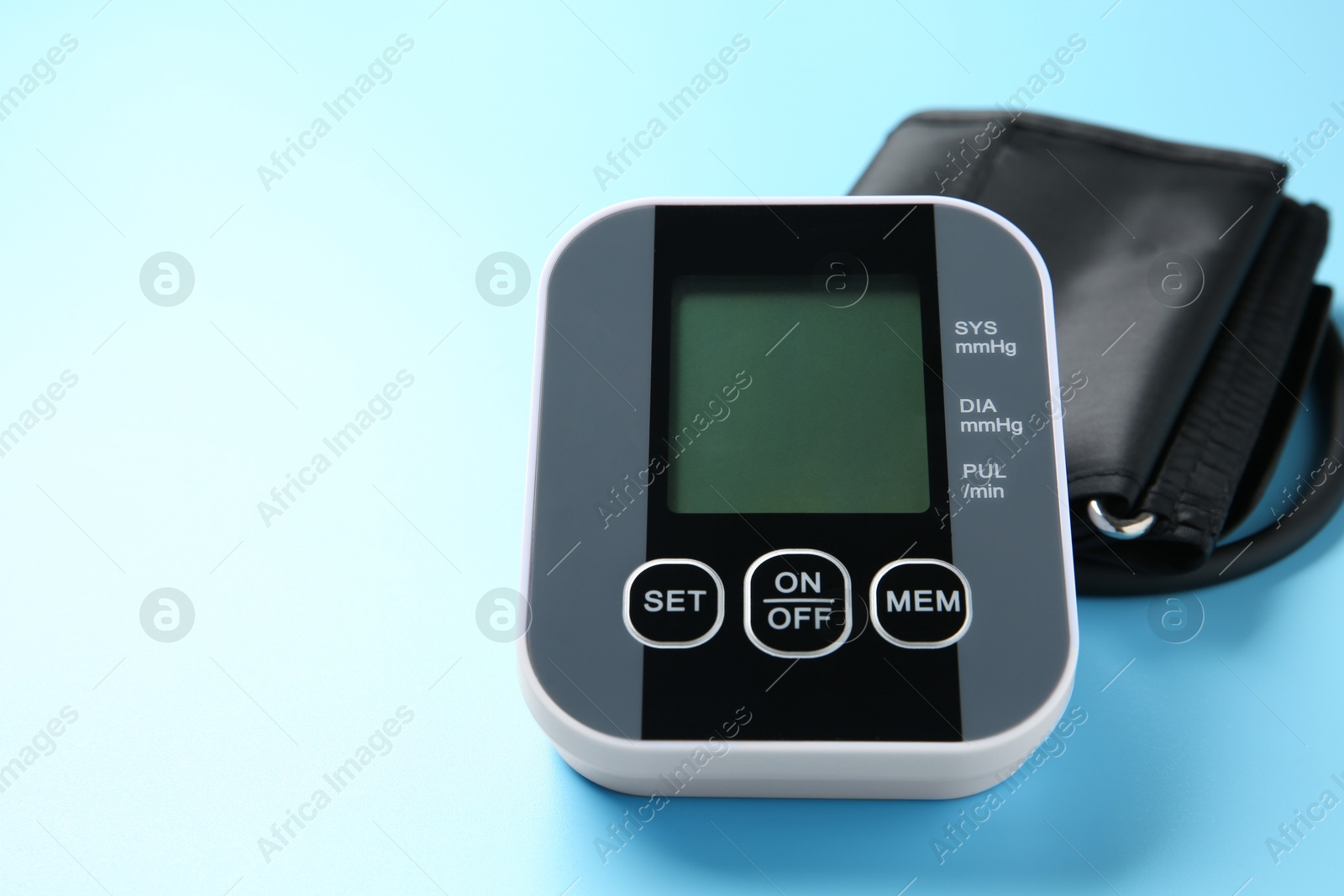 Photo of Blood pressure measuring device on light blue background, closeup. Space for text