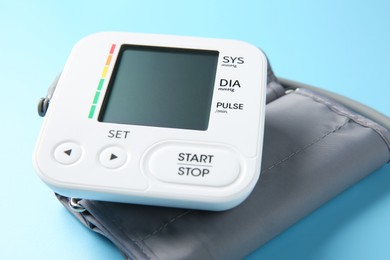 Photo of Blood pressure measuring device on light blue background, closeup