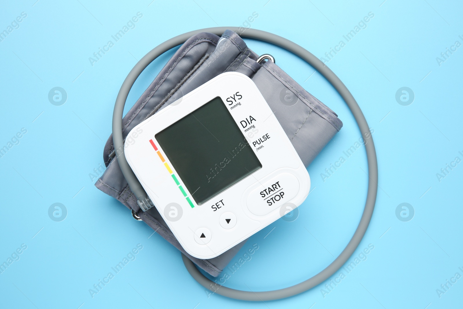 Photo of Blood pressure measuring device on light blue background, top view