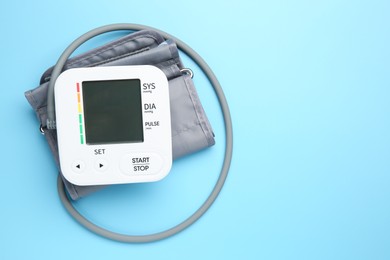 Blood pressure measuring device on light blue background, top view. Space for text