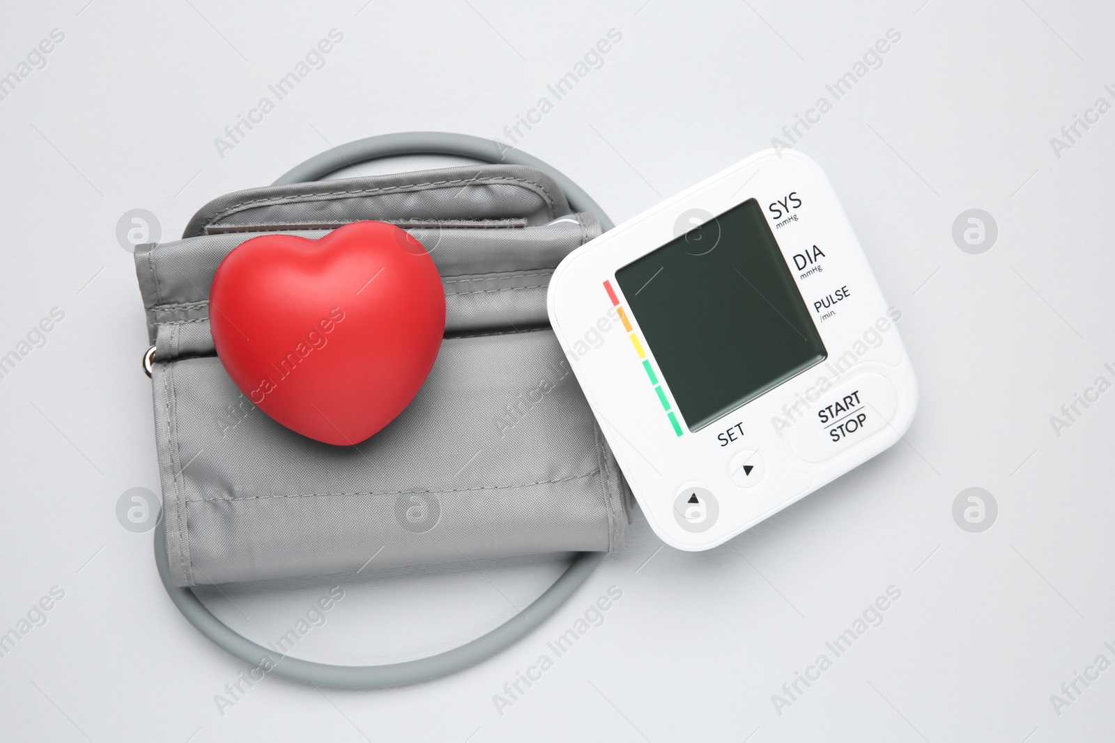 Photo of Blood pressure measuring device and squeeze heart on light grey background, top view