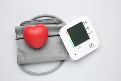 Photo of Blood pressure measuring device and squeeze heart on light grey background, top view