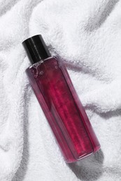 Photo of Shampoo in bottle on soft towel, top view