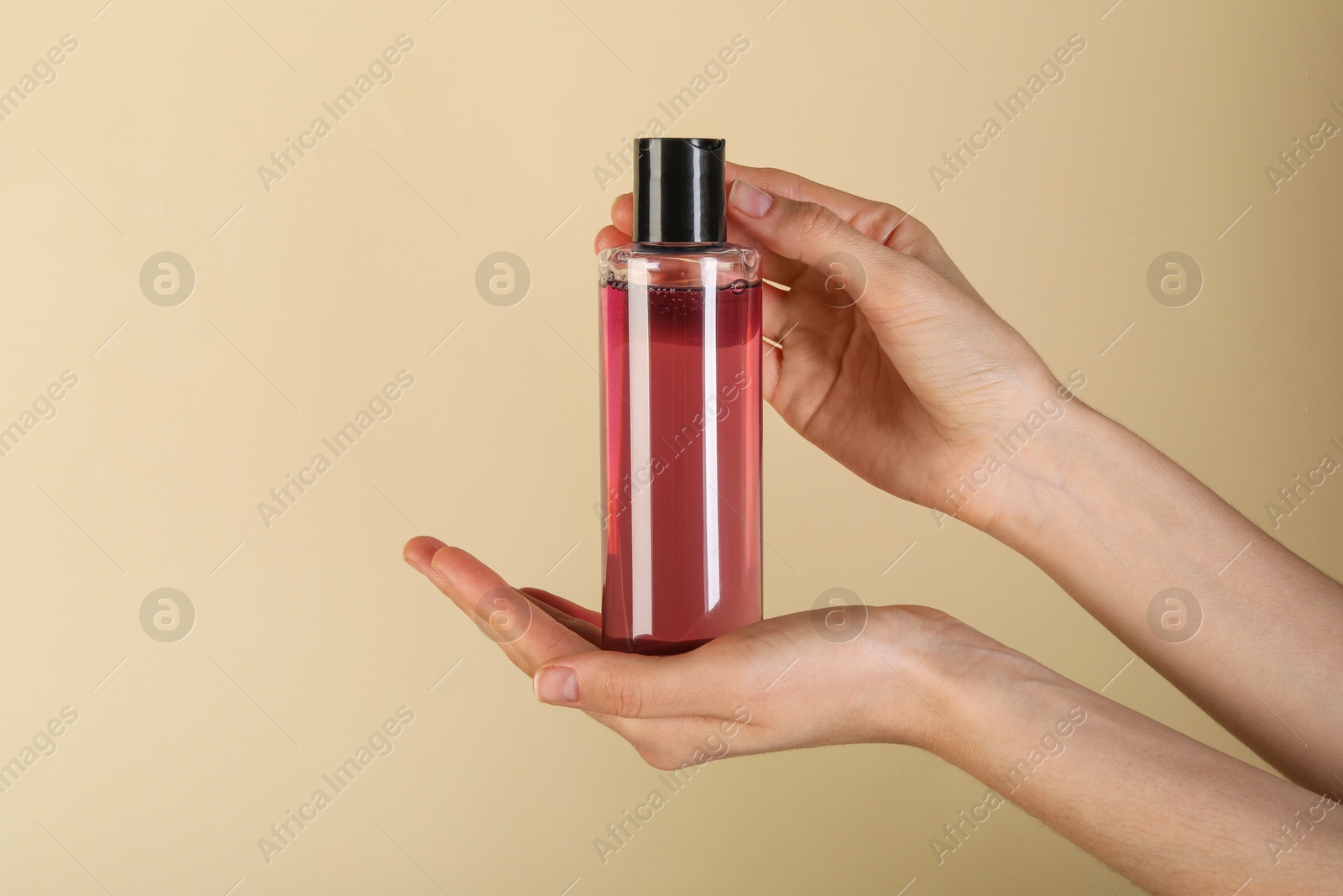 Photo of Woman with shampoo bottle on beige background, closeup