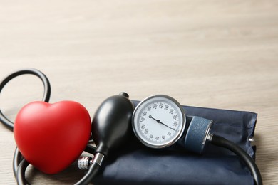 Photo of Blood pressure measuring device and squeeze heart on wooden table