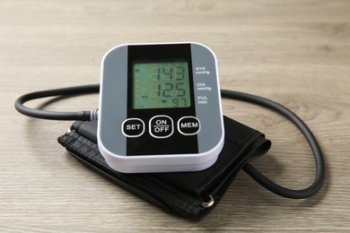 Photo of Blood pressure measuring device on wooden table, closeup