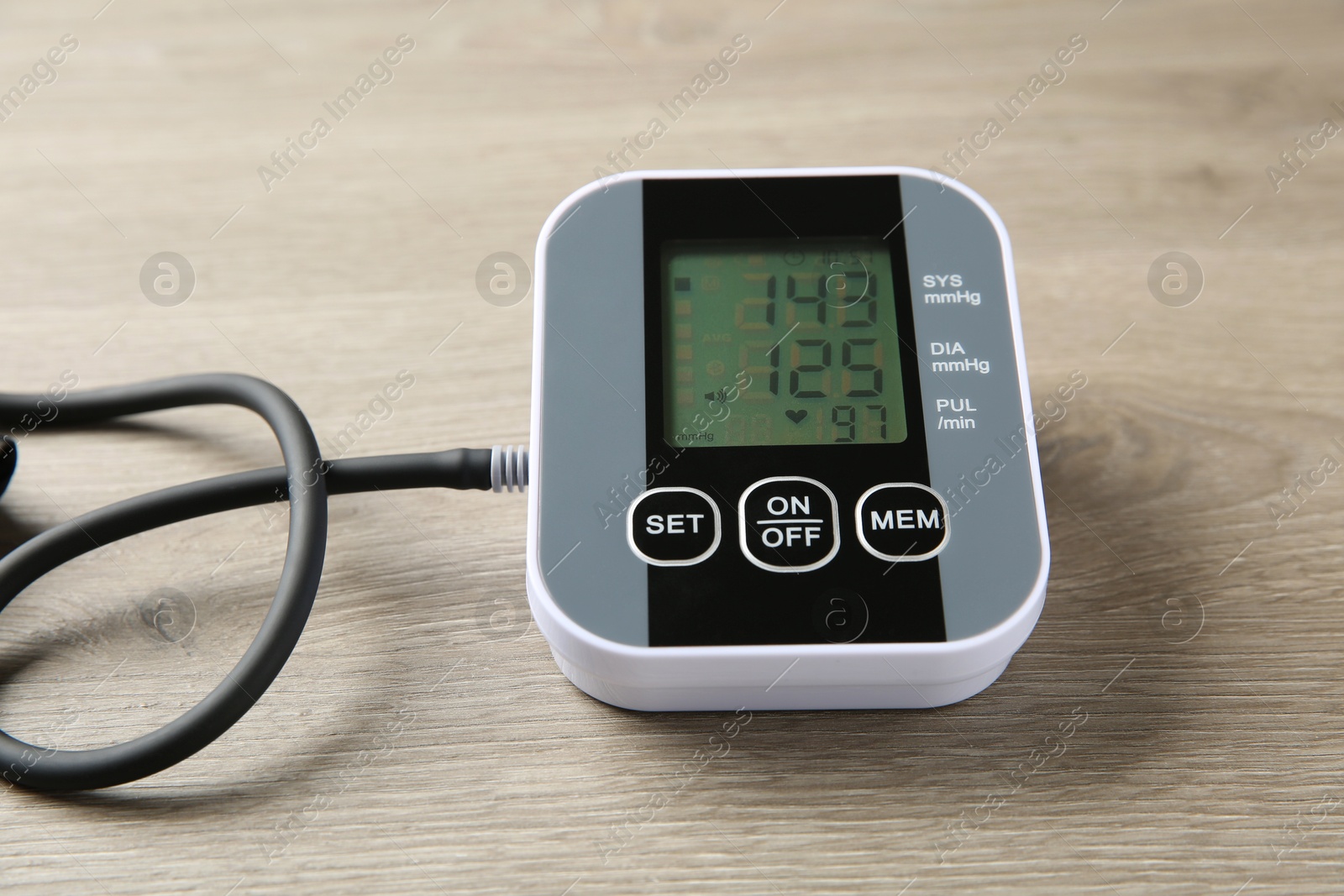 Photo of Blood pressure measuring device on wooden table, closeup