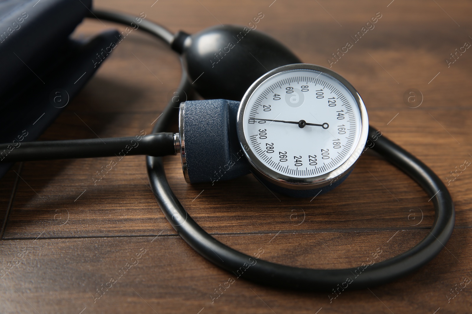 Photo of Blood pressure measuring device on wooden table, closeup