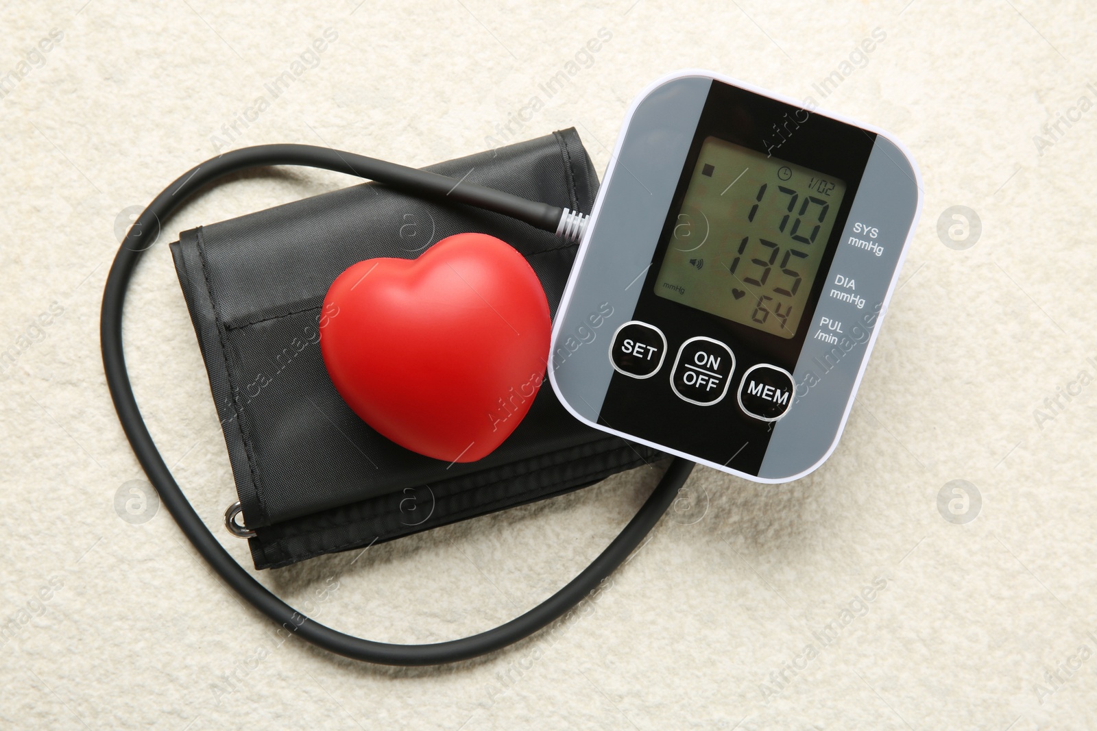 Photo of Blood pressure measuring device and squeeze heart on light textured background, top view