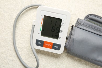 Photo of Blood pressure measuring device on light textured background, top view