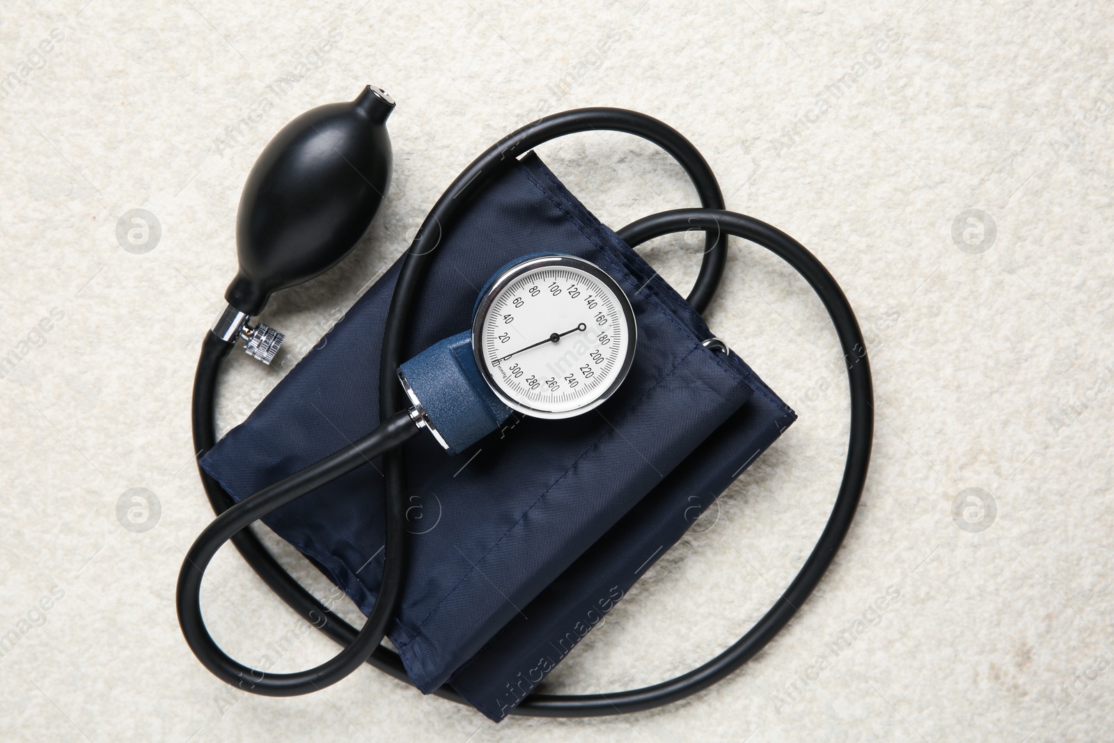 Photo of Blood pressure measuring device on light textured background, top view