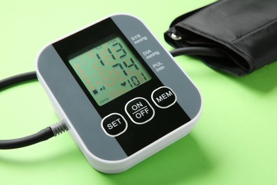 Photo of Blood pressure measuring device on green background, closeup