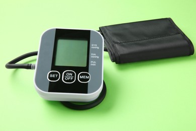 Photo of Blood pressure measuring device on green background, closeup