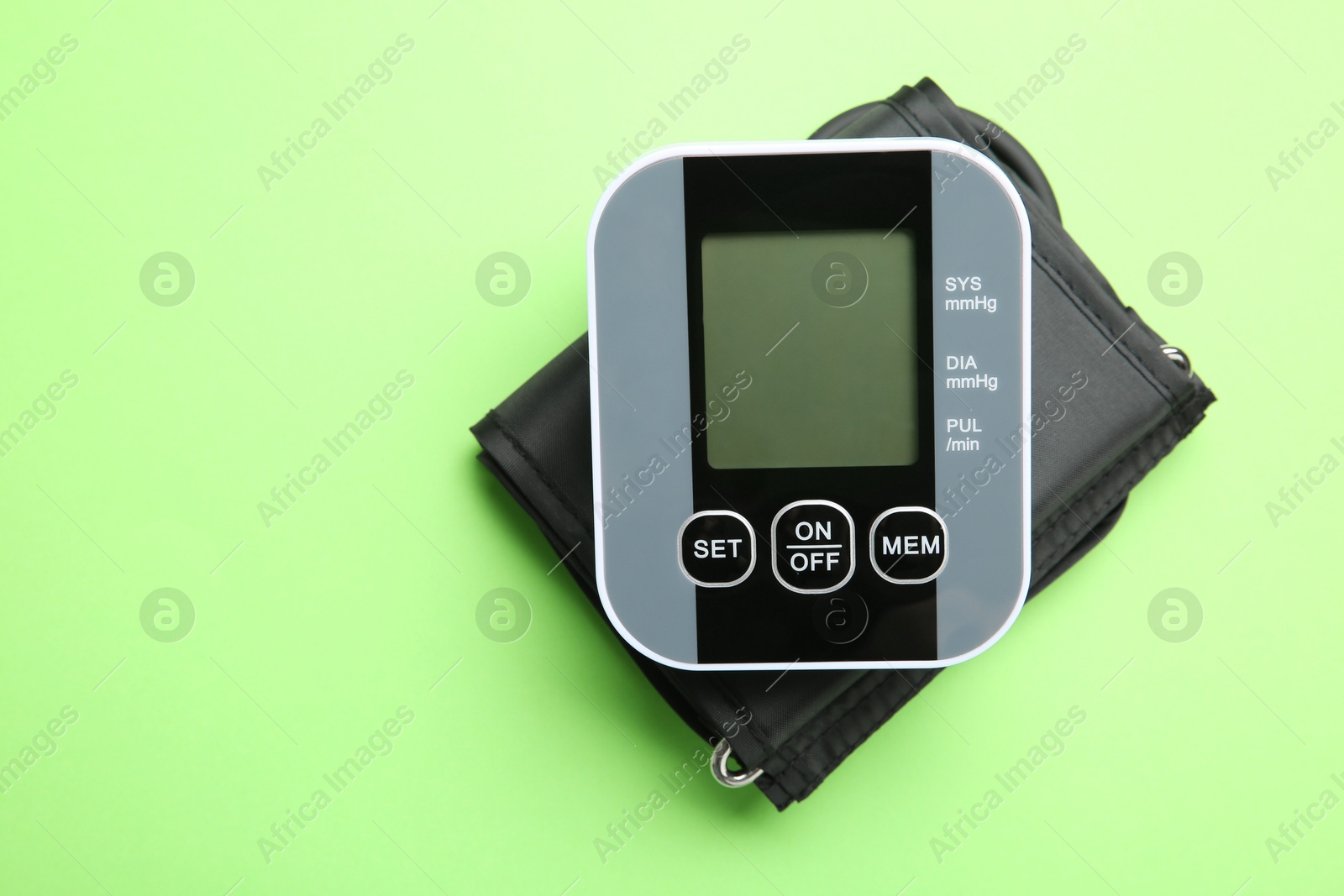 Photo of Blood pressure measuring device on green background, top view. Space for text