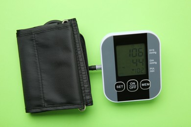 Photo of Blood pressure measuring device on green background, top view