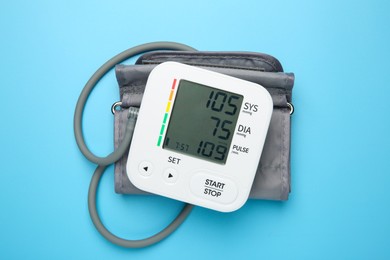 Photo of Blood pressure measuring device on light blue background, top view