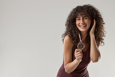 Photo of Happy winner with bronze medal on light grey background. Space for text