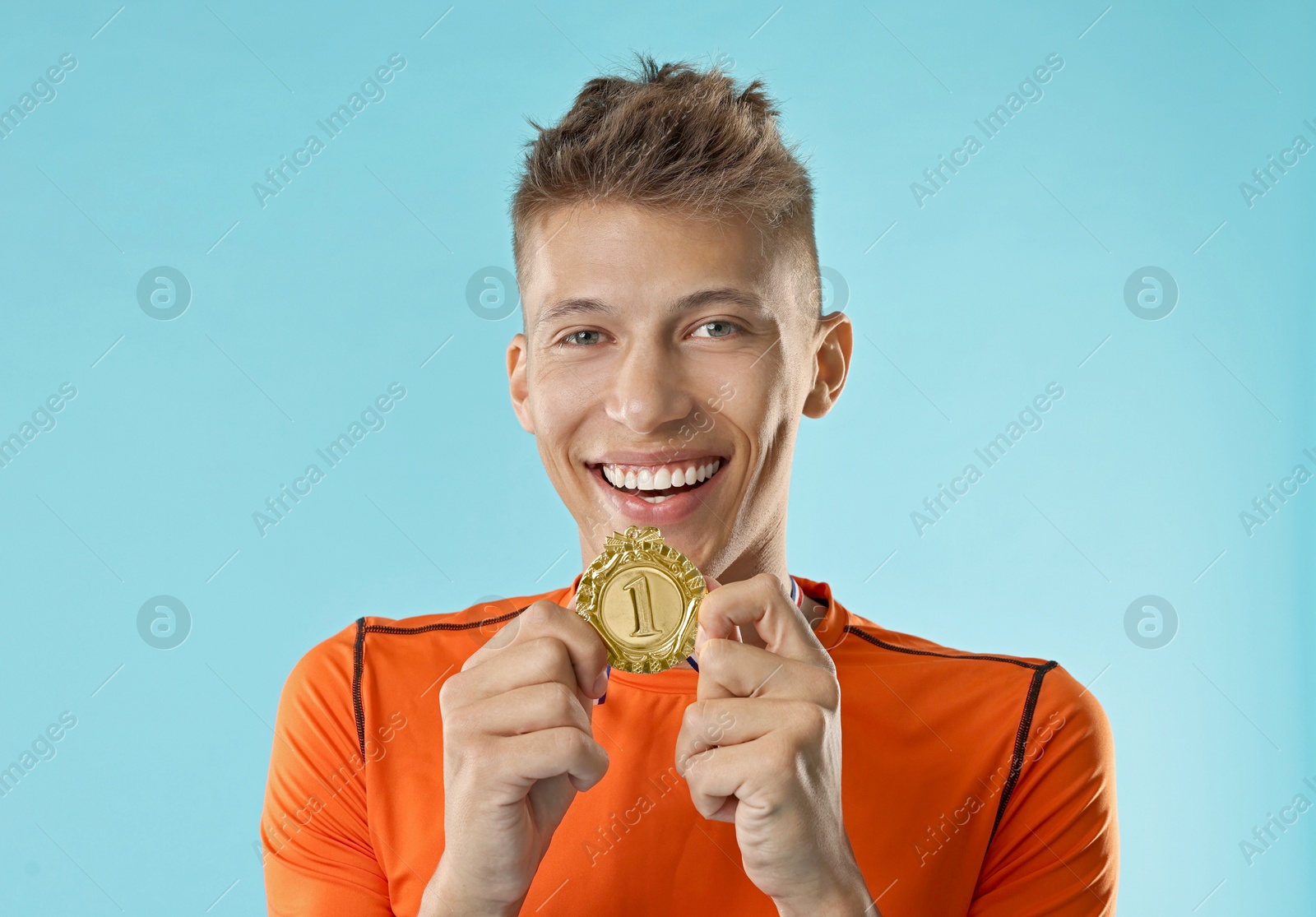 Photo of Happy winner with golden medal on light blue background